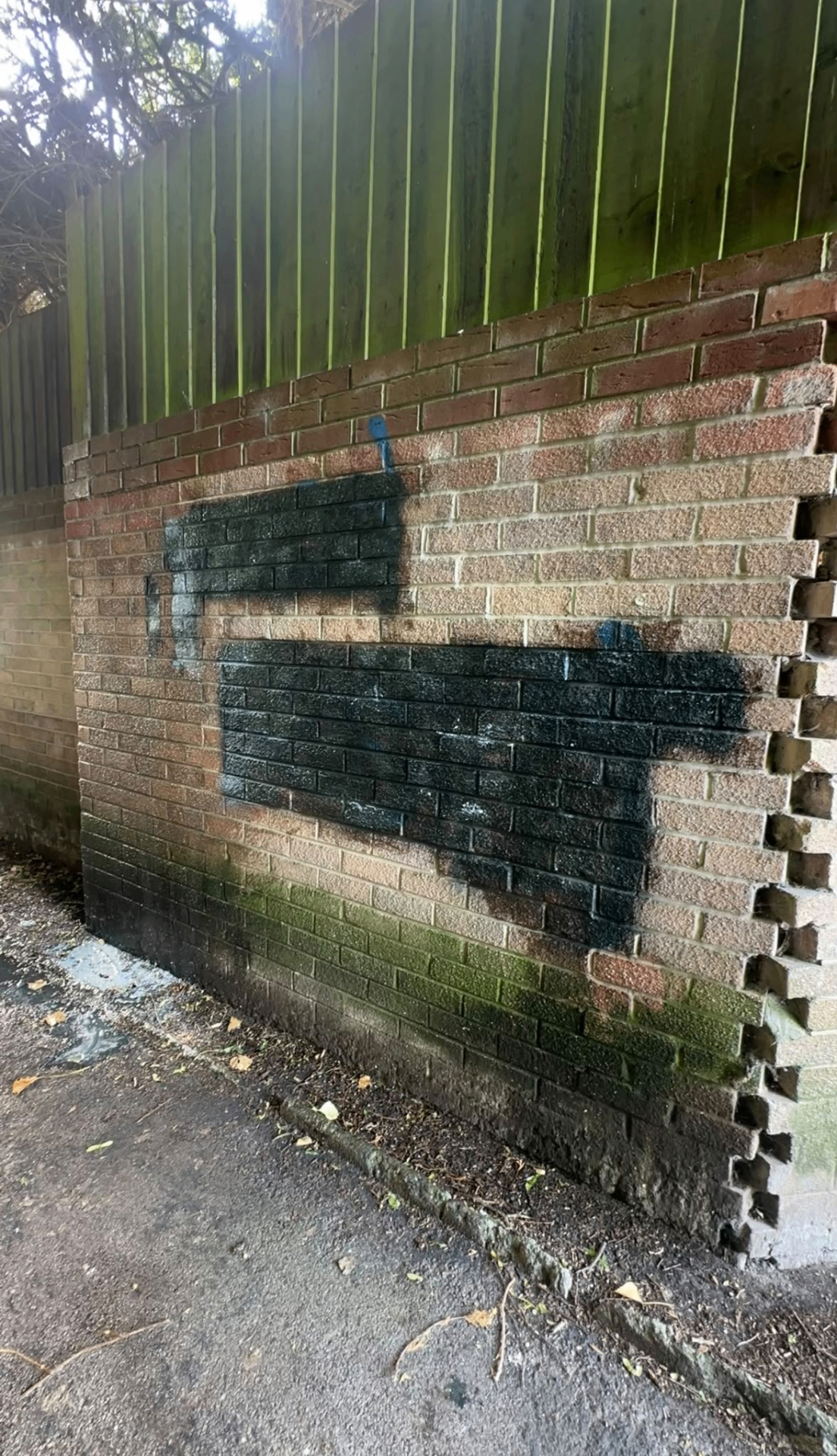 Graffiti sprayed across a brick boundary wall before professional cleaning and restoration