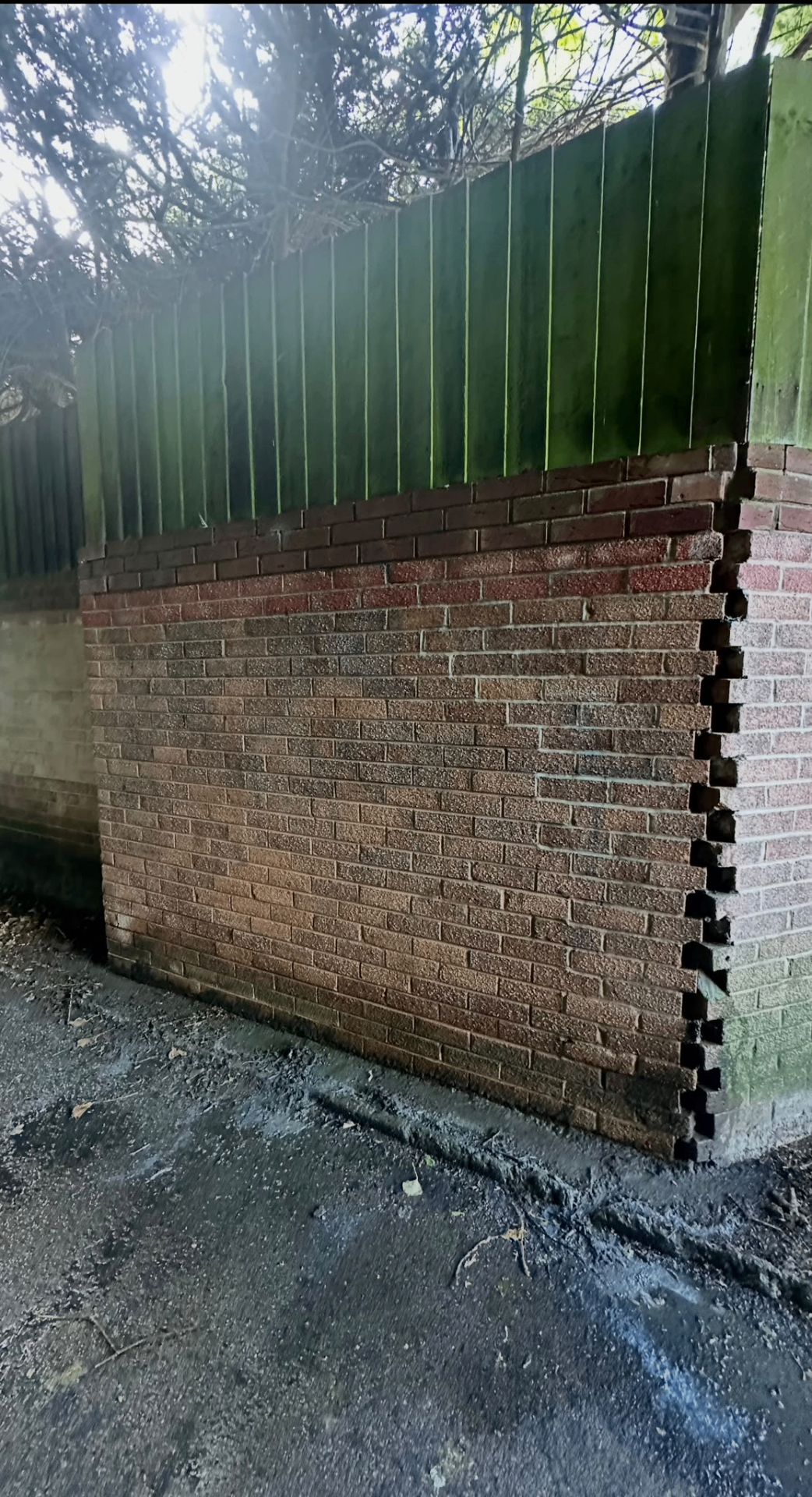 After graffiti cleaning: the same brick boundary wall restored with the spray paint removed